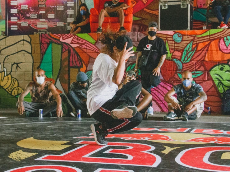 skateboarder performing trick for audience in front of graffiti wall