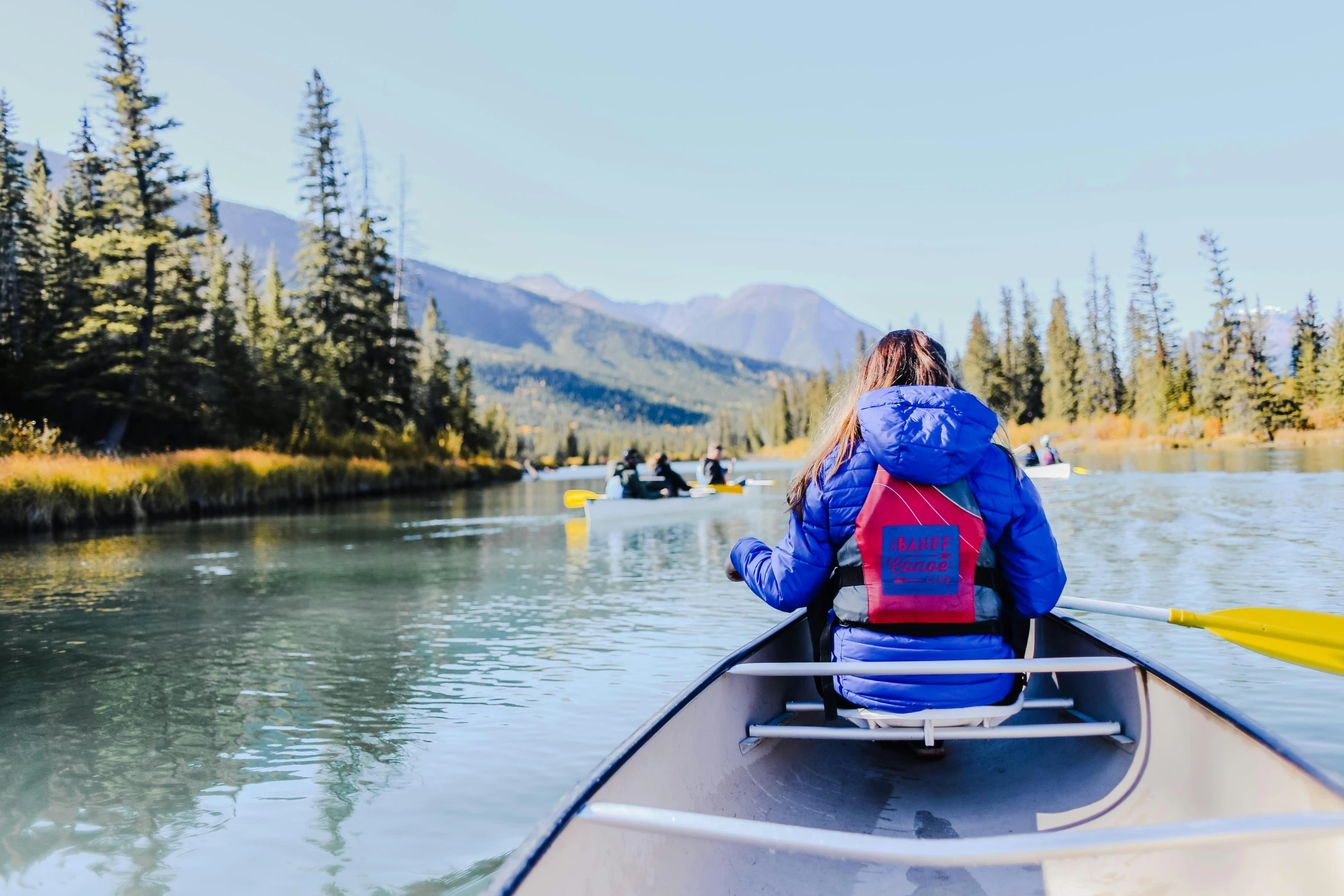 a woman riding in a boat next to a forest