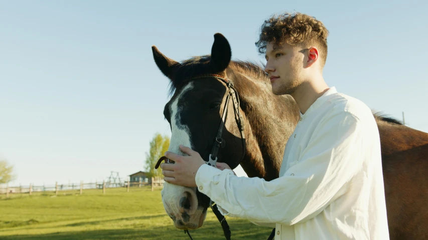 the man stands close to a horse that is by him