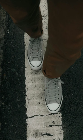 someone standing next to their feet in sneakers