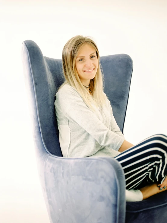 woman posing for po in blue chair with grey walls