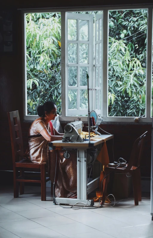 a woman sitting at a table working on a computer