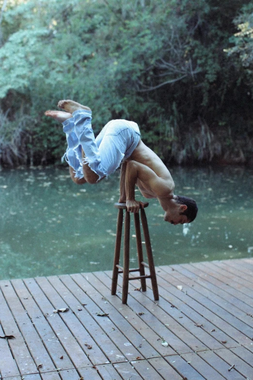 man is balancing on chair over river by himself