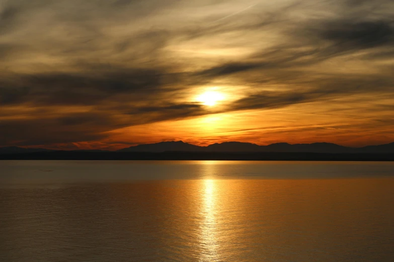 a couple of people sitting on a bench watching the sunset