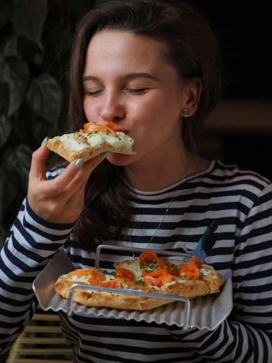 a woman eating a piece of pizza while sitting at a table