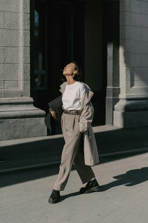 a person standing on a sidewalk, with a bag and jacket on