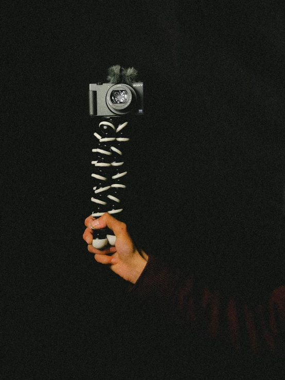 a person in a dark room holds an old camera and the camera is holding it