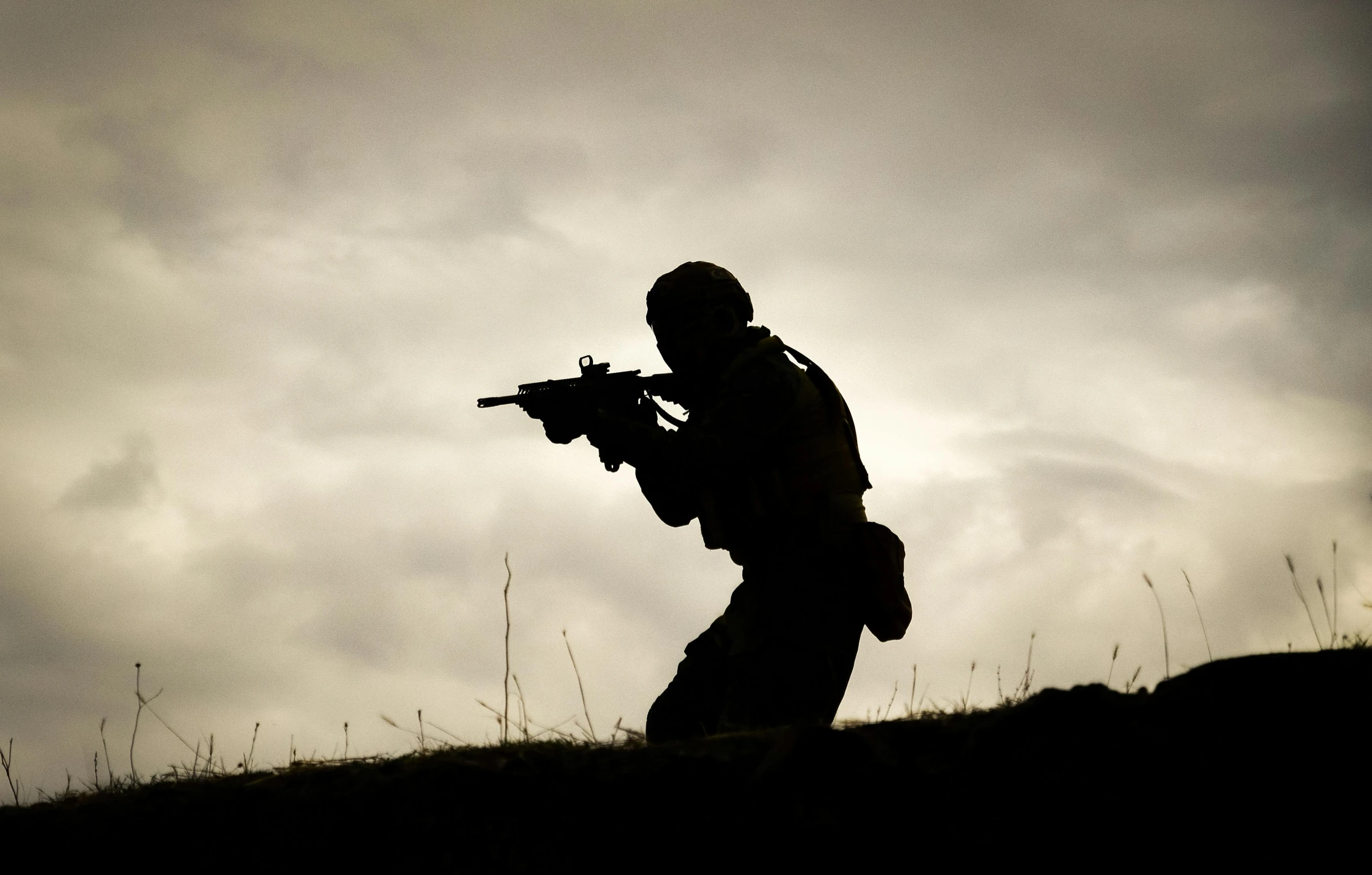 a person that is walking in the grass with a gun