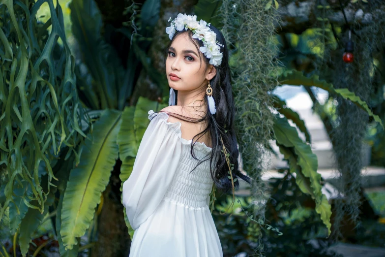 girl wearing a flower head piece while standing among greenery