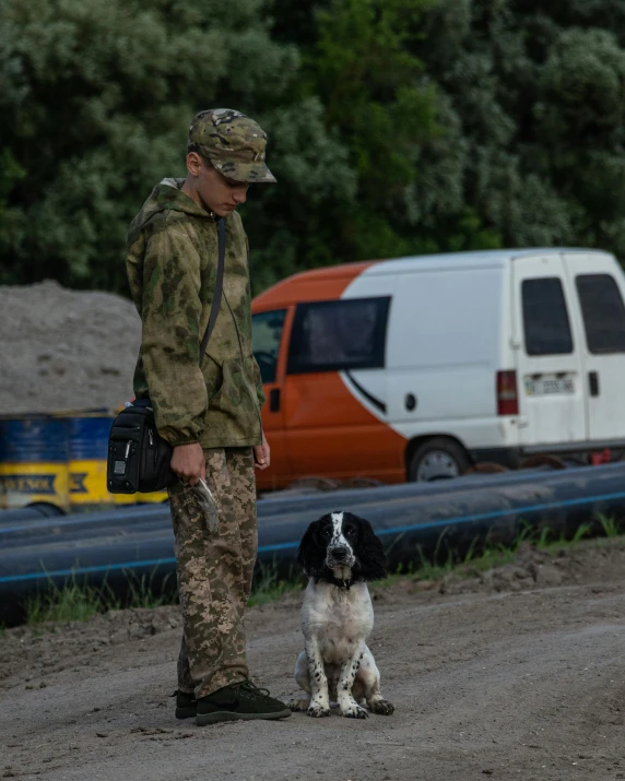 a person that is standing in the dirt with a dog