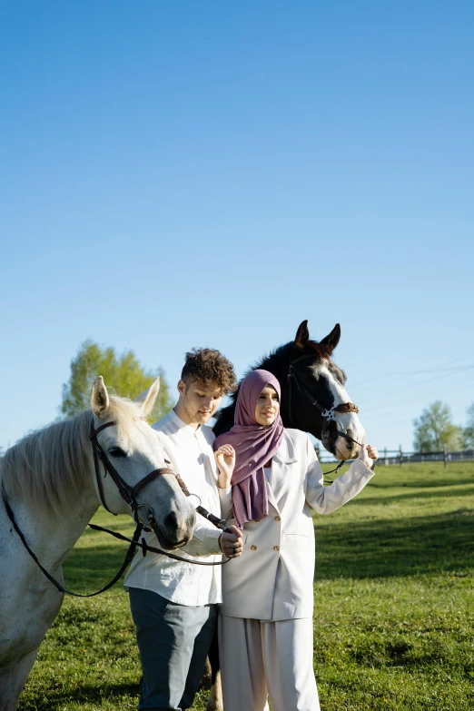 two people are standing with a horse in a grassy field