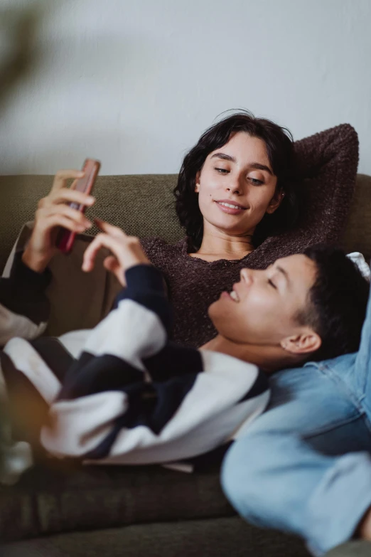 a boy laying on a couch and woman taking a po