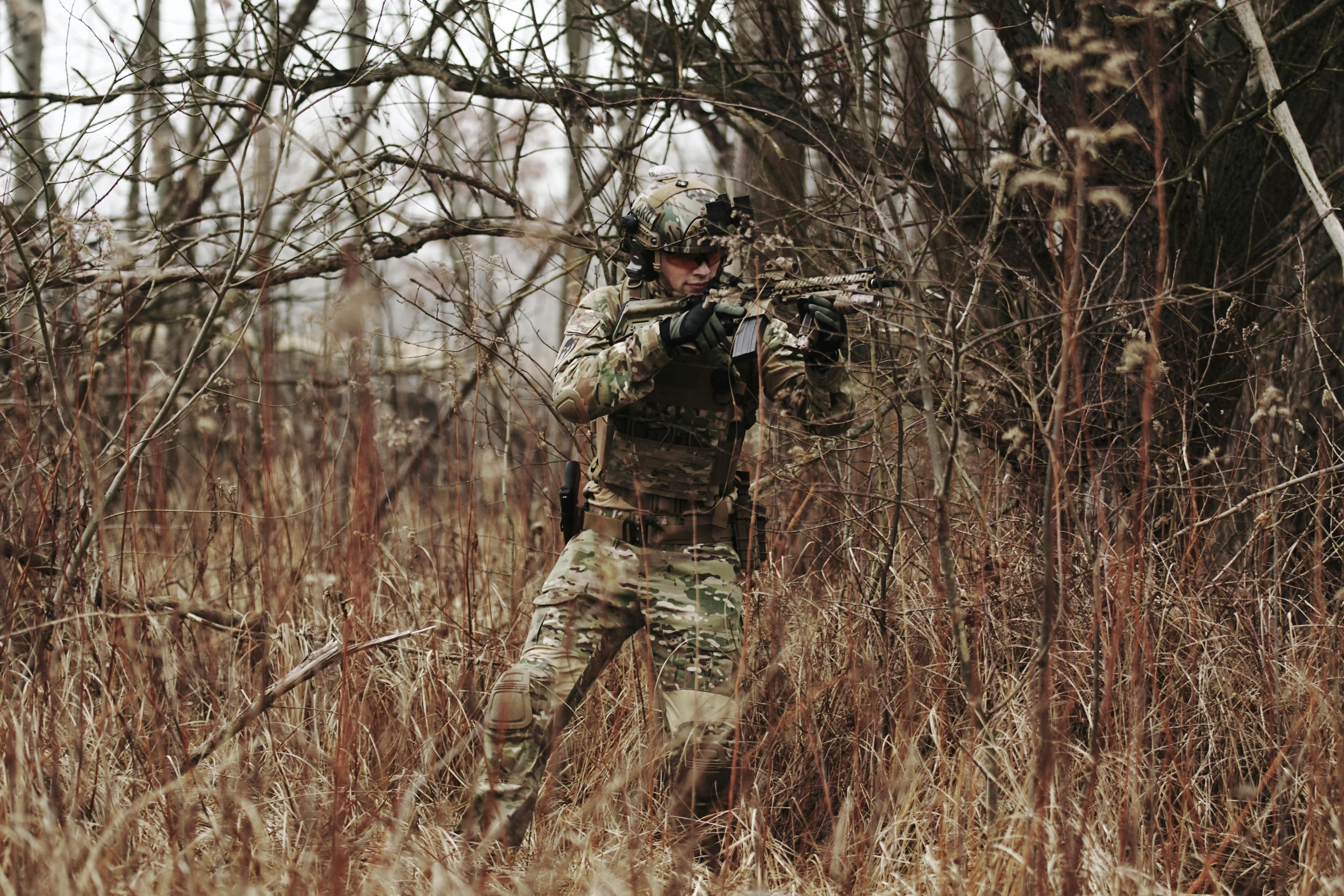 a soldier standing in the middle of a field next to trees