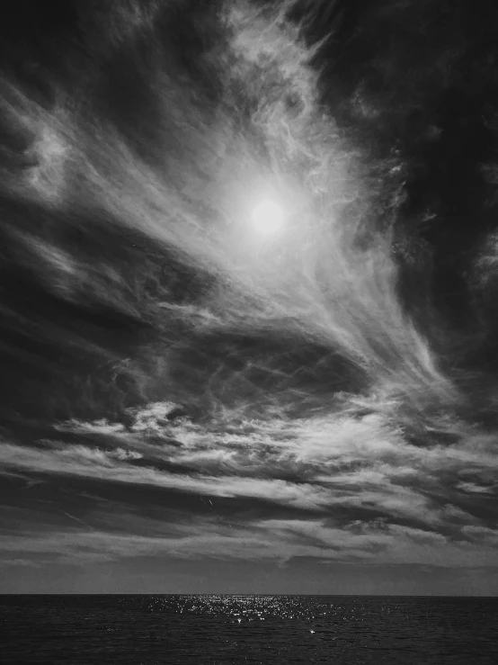 a black and white po of clouds above the ocean