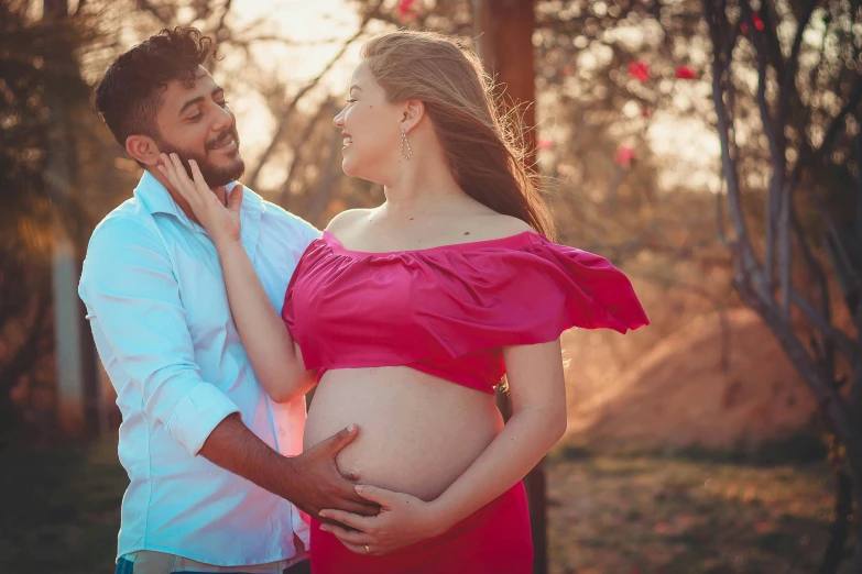 the pregnant couple is posing for a picture in their natural surroundings