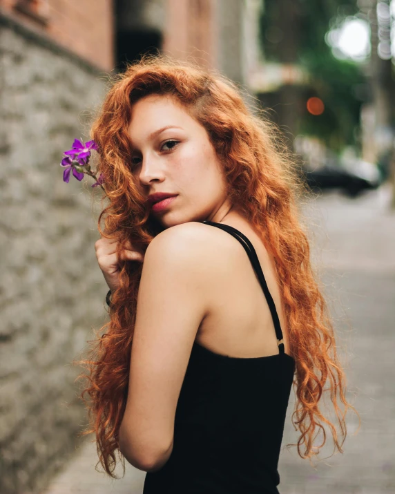 the girl is holding a flower with red hair