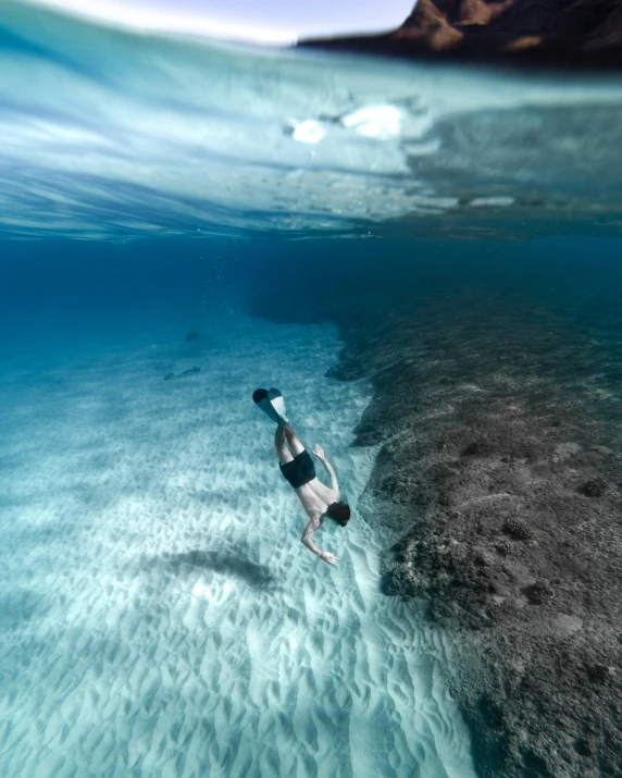 a man dives underwater in to the sea while surfing