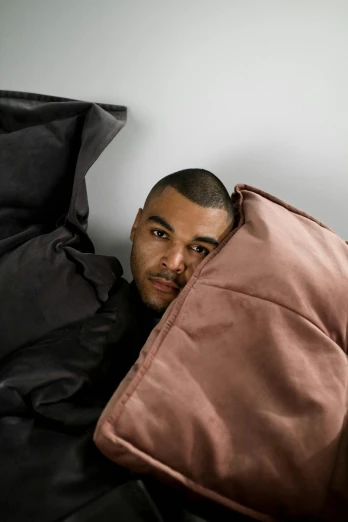 a man hiding behind a brown pillow and pillow case