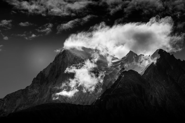 a dark sky with a cloud over mountain peaks