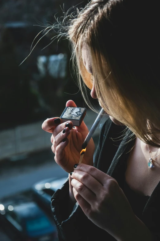 a young woman holding a cell phone while standing in front of a building