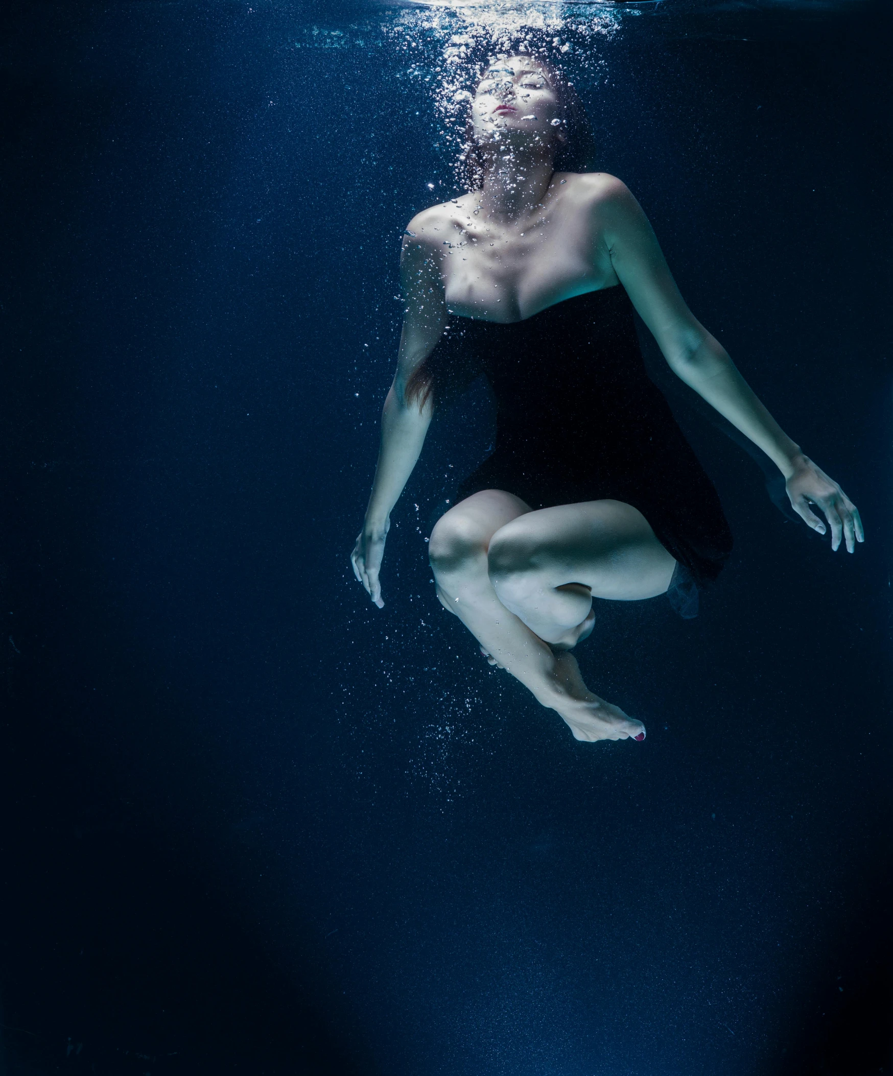 a woman in a bathing suit dives beneath water