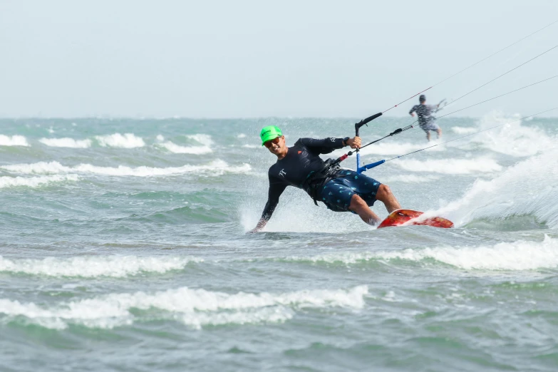 a guy windsurfs on the ocean while another man watches from his surfboard