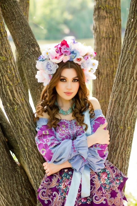  in purple dress and floral headpiece sitting in tree