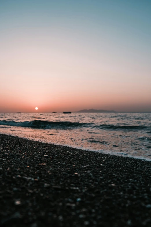 the sun rising over the ocean and the beach