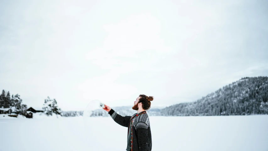 a woman stands in the snow, holding out her hand