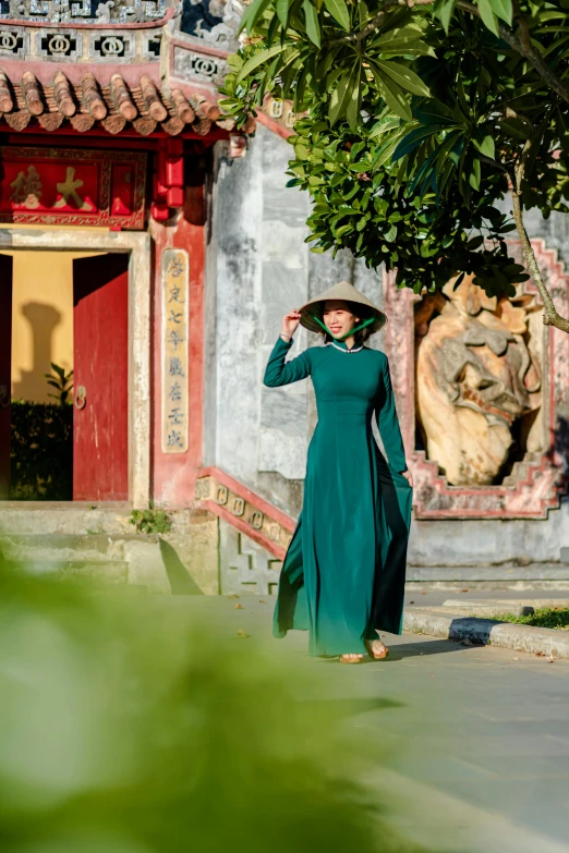 a woman wearing a long green dress is looking over her shoulder