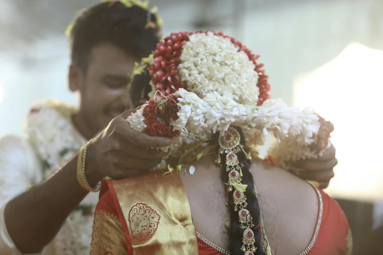 man fixing white flower arrangements on a woman's hair