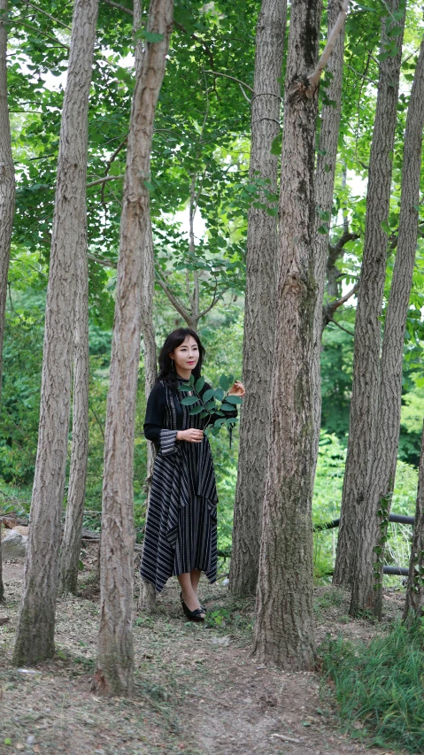 a woman standing near a bunch of trees
