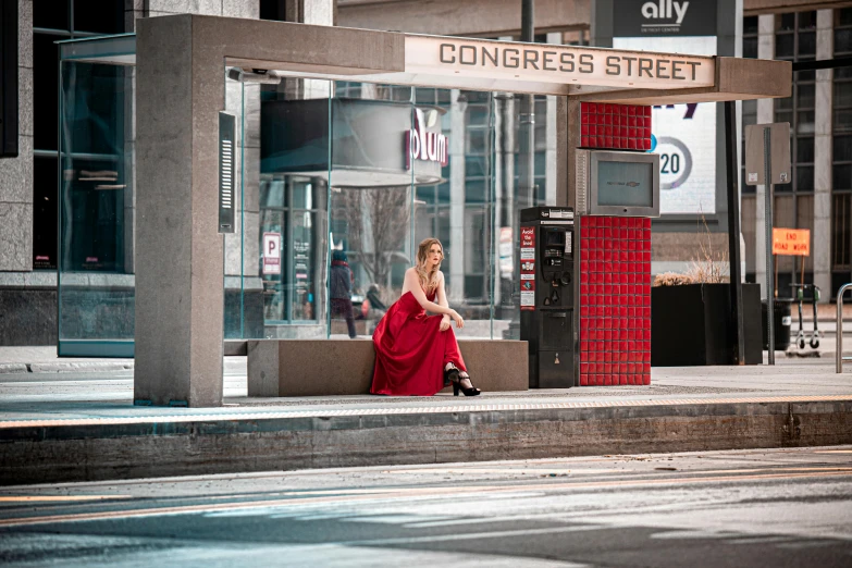 a lady in a red dress is on her phone on a sidewalk