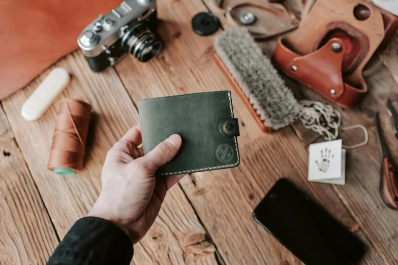 someone is holding a leather wallet near a camera