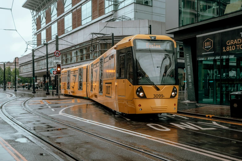 yellow train traveling down a rainy city street