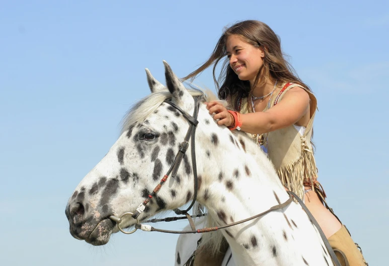 a girl is sitting on a white horse and smiling