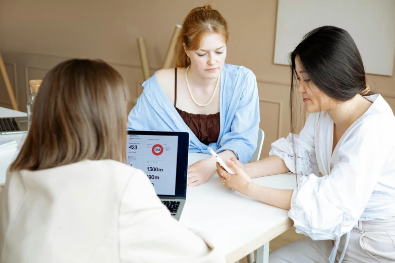 two young ladies are talking in front of a computer screen