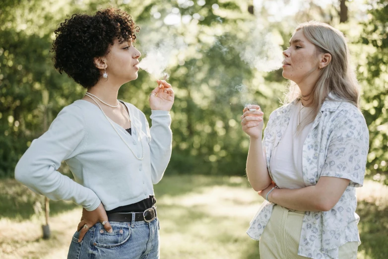 two women standing near each other, blowing on one another's fingers