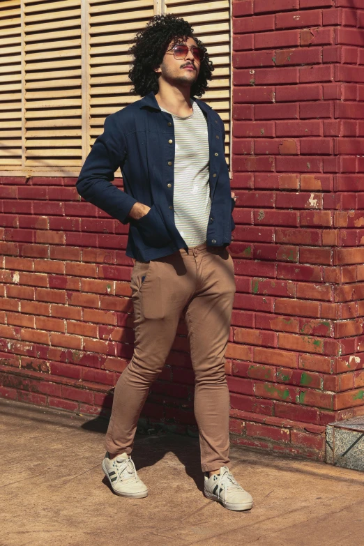 a man in blue jacket leaning against red brick wall