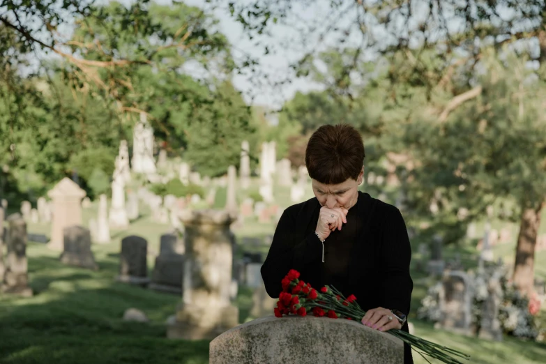 woman in black jacket standing at a grave