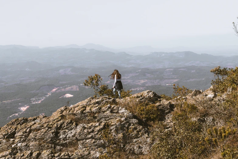 a woman standing on top of a rock covered mountain