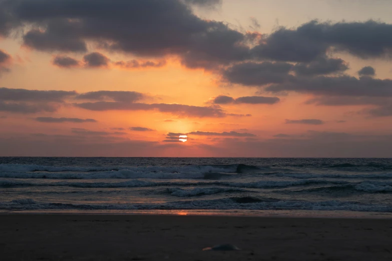 a person is walking on a beach at sunset