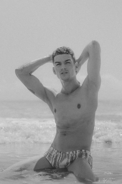 a man in bathing trunks sitting on a beach