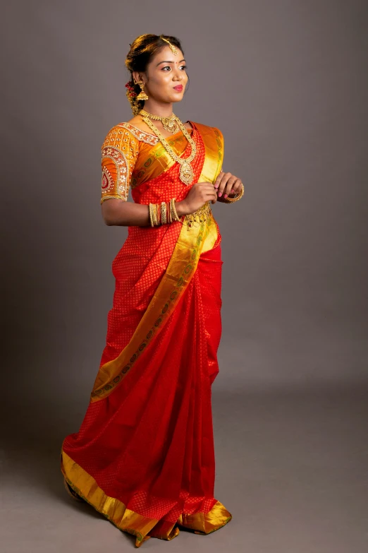 a beautiful young lady in a red and gold sari