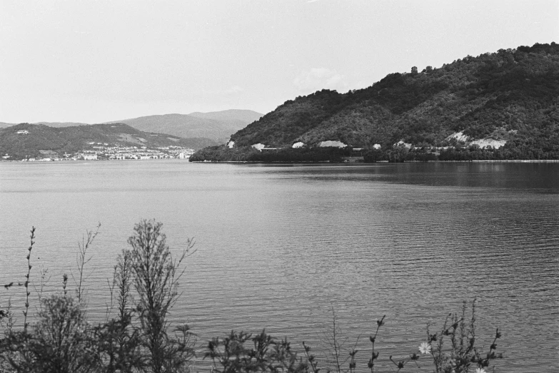 a black and white pograph of water with hills in the background