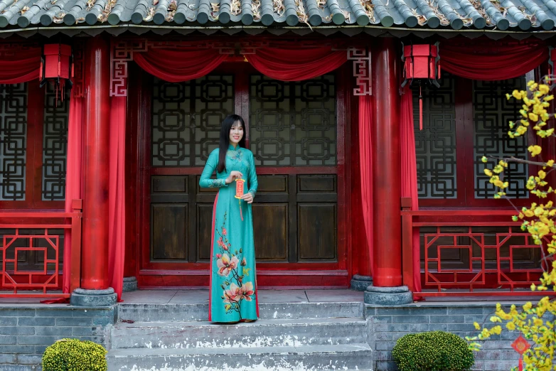 an asian woman standing in front of an ornate, red building