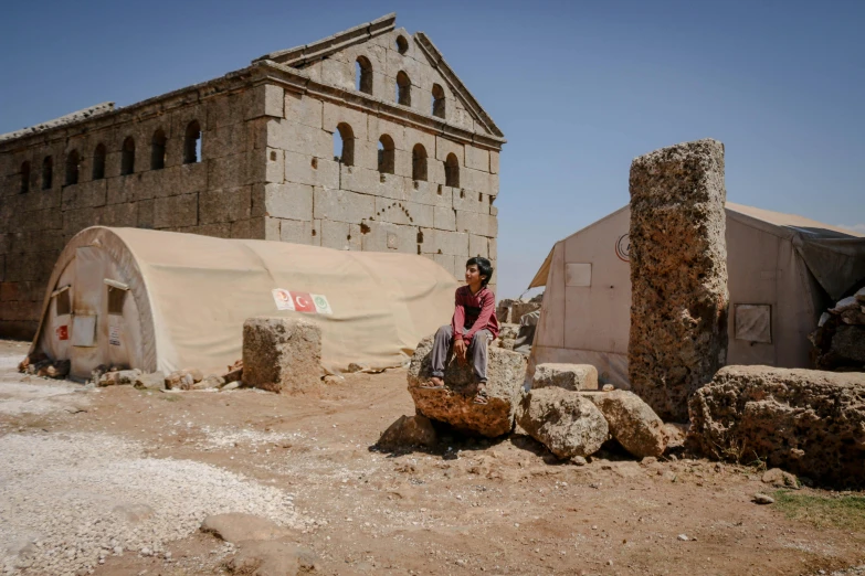 a girl is sitting on some rocks in a village