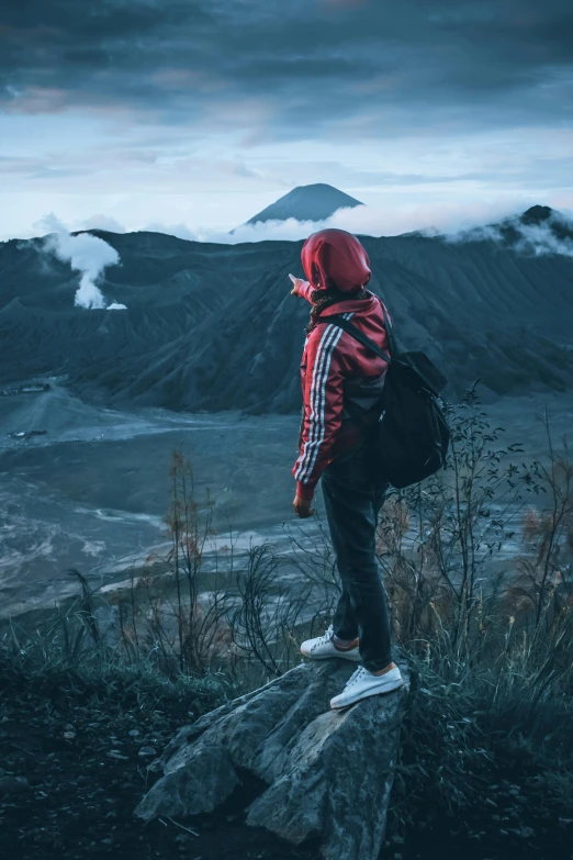 a person in a hood and jacket standing on a hill