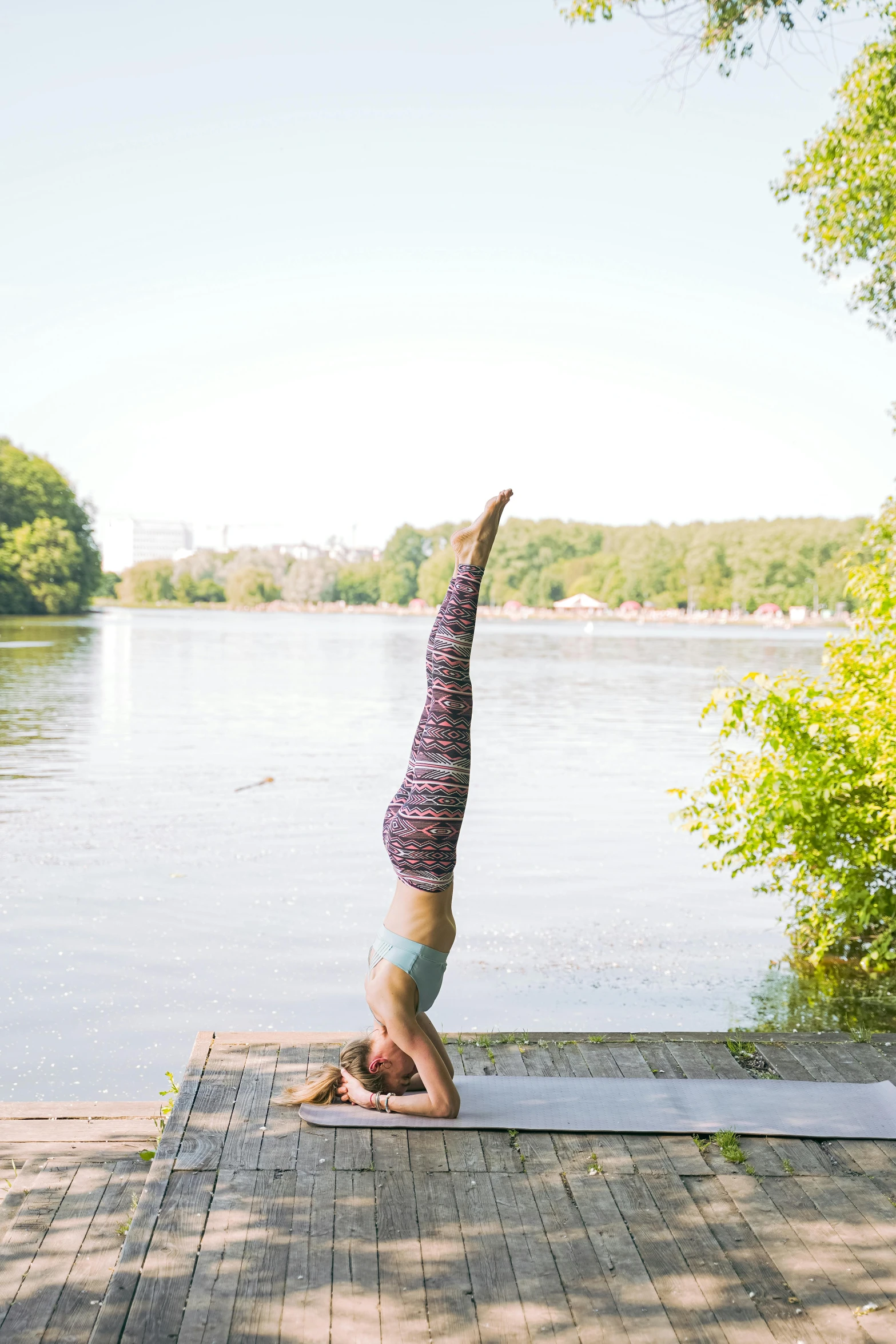 person doing the splitstand on a dock by a lake