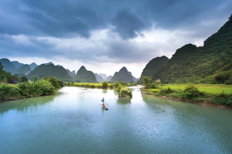 a man paddles through the river surrounded by mountains